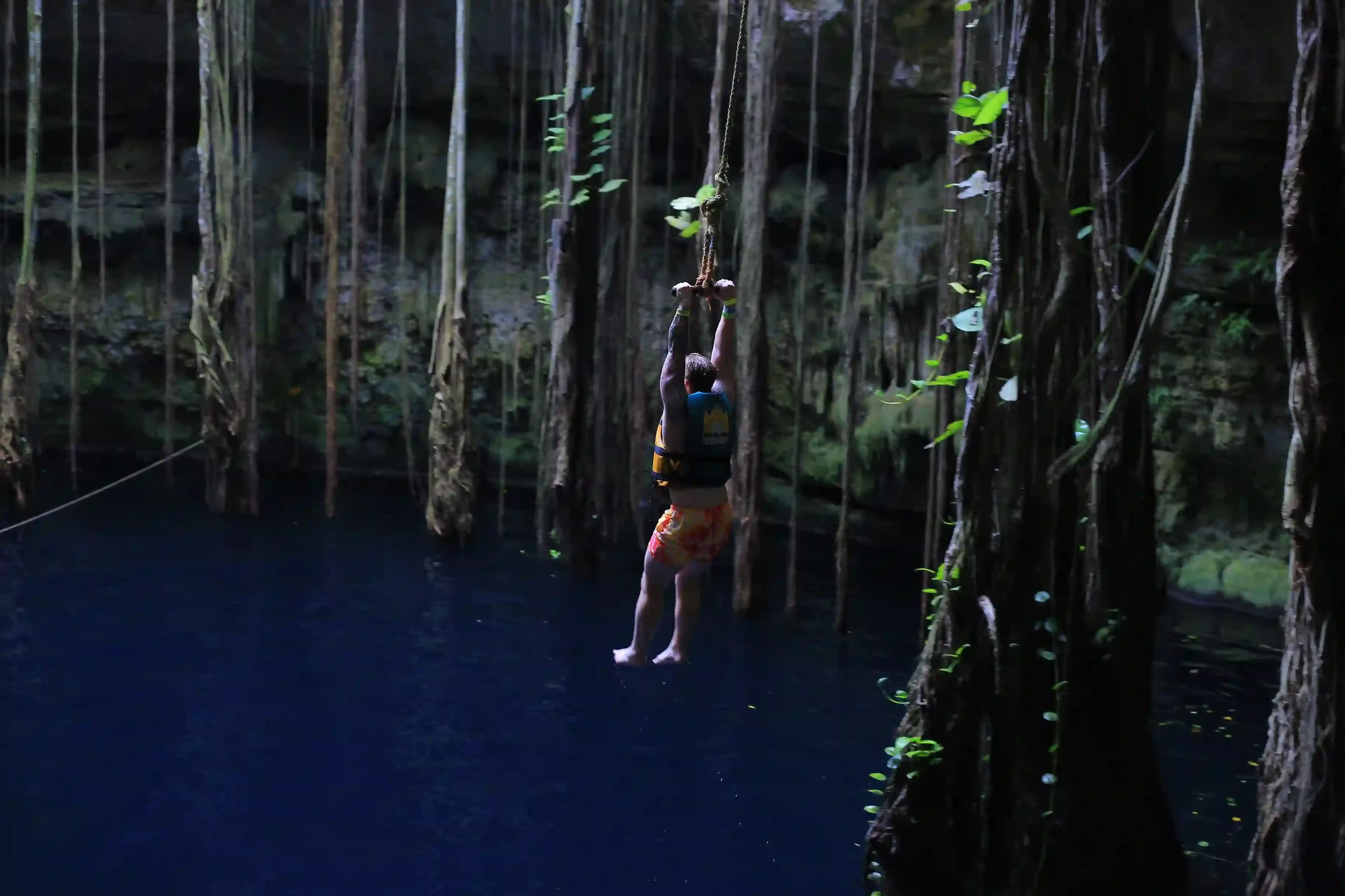 Hombre pasando en cuatrimoto por un cenote